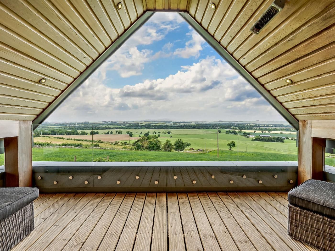 A room with a sloped ceiling and a large window offering a view of a green landscape.