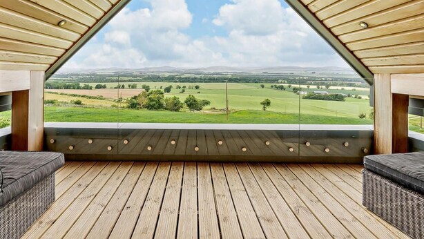 Eine dreieckige Holzbalkendecke mit Blick auf eine grüne Landschaft.