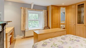 A bedroom with a bed, a desk, a chair, a radiator, a window with curtains, and wooden doors. - 4 Bed in Tavistock (oc-92491) (Gulworthy)