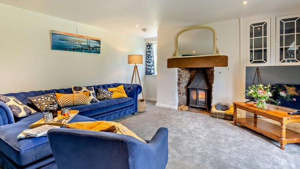 Ein Wohnzimmer mit blauem Sofa, Kamin, Gemälde und Lampe.