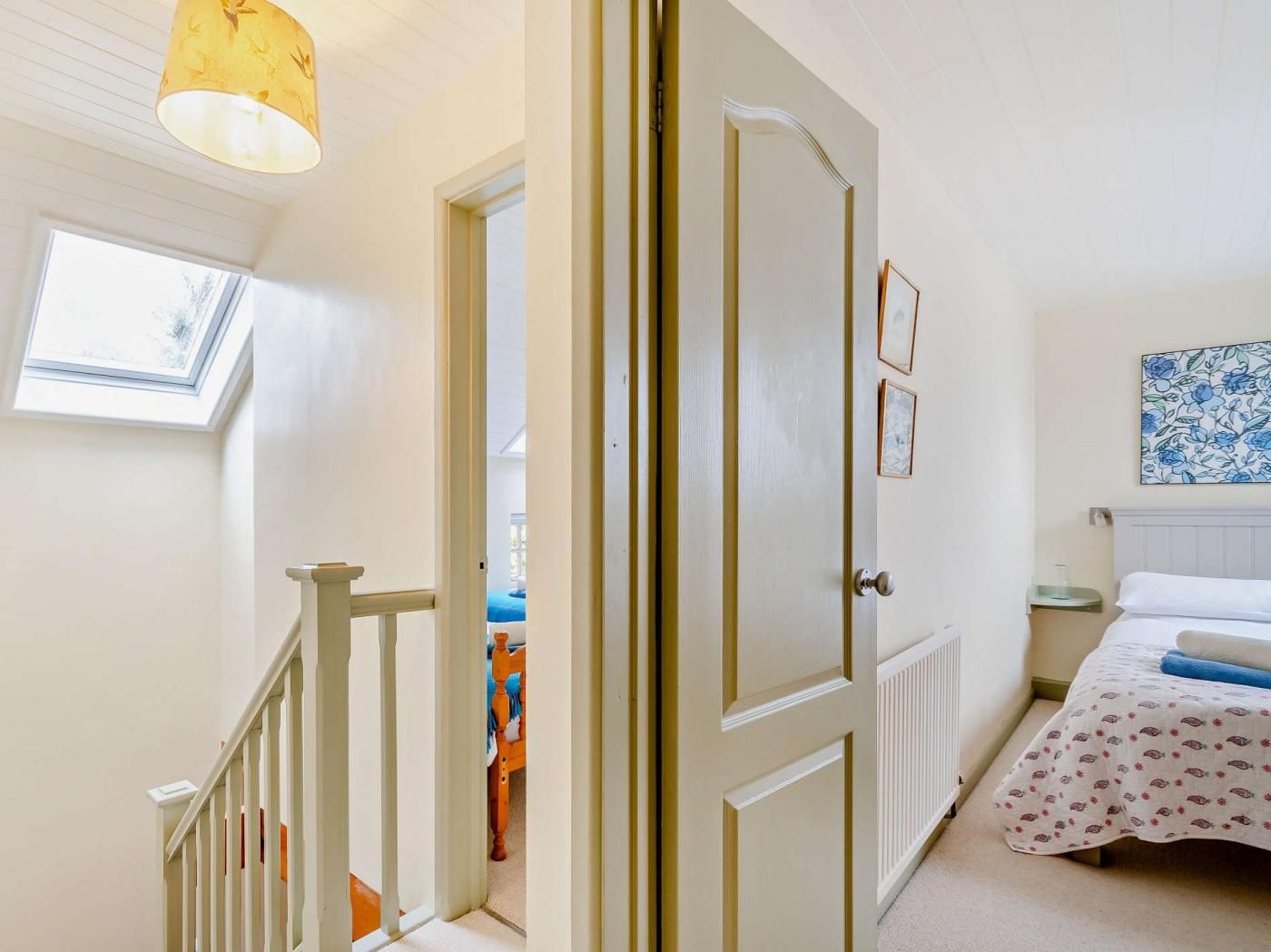 Een slaapkamer met een bed, een radiator, een nachtkastje, een ingelijst foto en een raam met uitzicht.