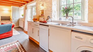 Une cuisine moderne avec des appareils électroménagers blancs, un mur d’accent en pierre et une grande fenêtre donnant sur un paysage verdoyant.