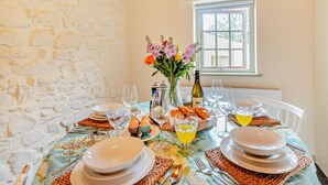 Une table à manger dressée avec des assiettes, des verres et un vase rempli de fleurs.