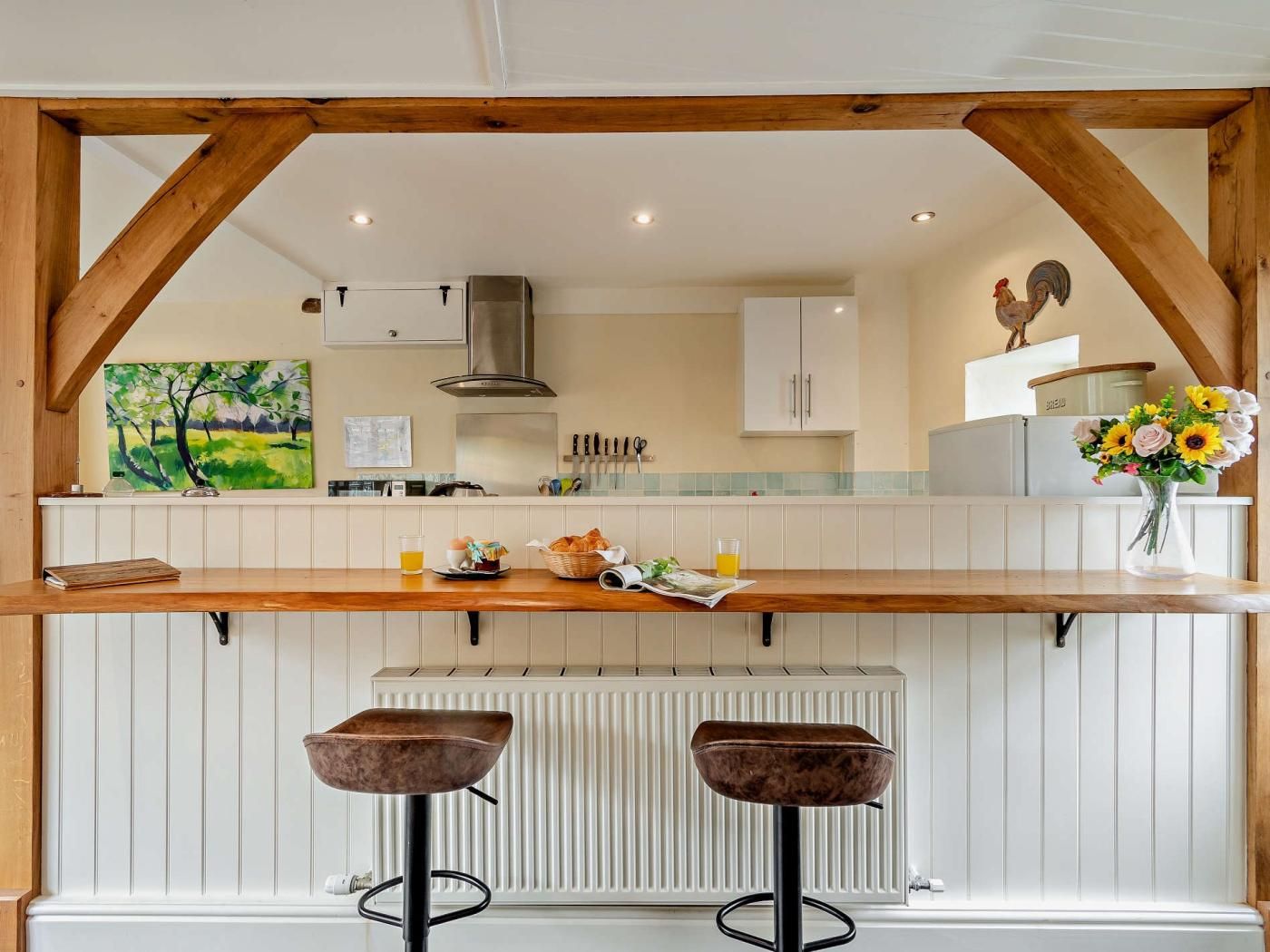 A kitchen with a wooden countertop, two stools, a radiator, and a rooster decoration.