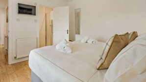 Una camera d'albergo con un letto, una TV, una porta e un termosifone.