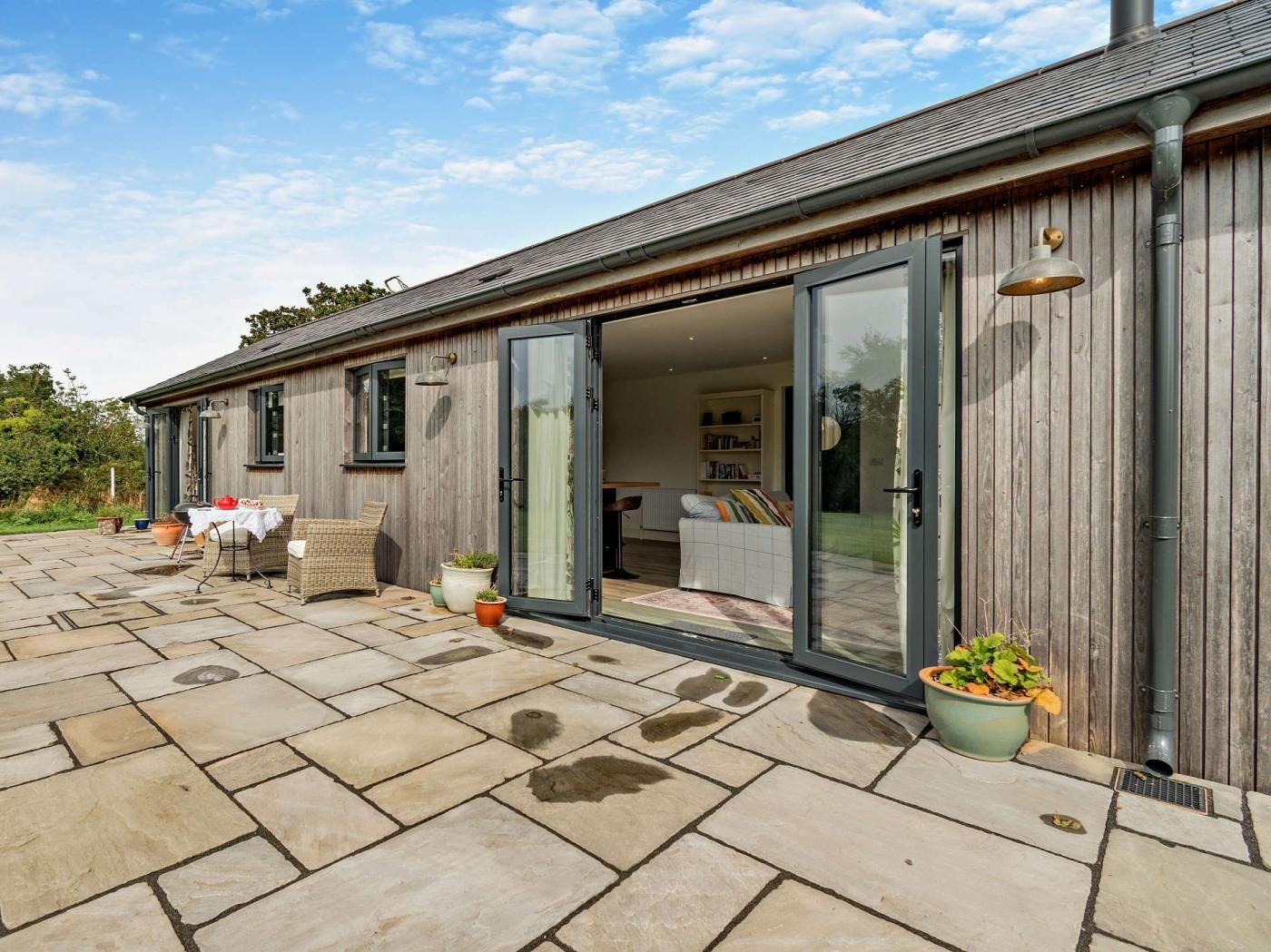 A modern house with a patio, sliding glass doors, and a conservatory.