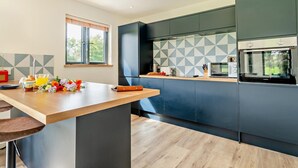 Eine moderne Küche mit Kochinsel, dunklen Schränken und einer geometrischen Spritzschutzwand.
