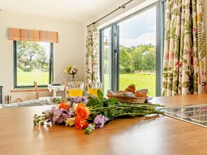 A dining table with a floral arrangement, croissants, and a glass of orange juice.