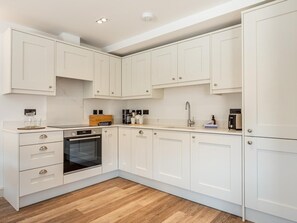 Eine moderne Küche mit weißen Schränken, einem eingebauten Backofen und einer Holz Arbeitsplatte.