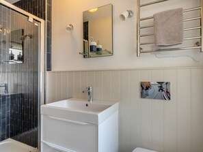 A modern bathroom with a white sink, a glass shower enclosure, a towel rack, and a mirror. - 1 Bed in Braunton (oc-92737) (Croyde)