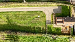 Ett flygbildsbild av en fastighet med en stor gräsyta, en asfalterad uppfart och en byggnad med ett sluttande tak.