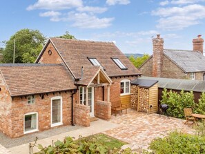 A brick house with a tiled patio, a wooden bench, and a grill area. - 1 Bed in Ludlow (oc-92768) (Hayton's Bent)