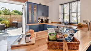 Eine moderne Küche mit einer großen Kochinsel, Holzarbeitsplatten und Blick in den Garten.