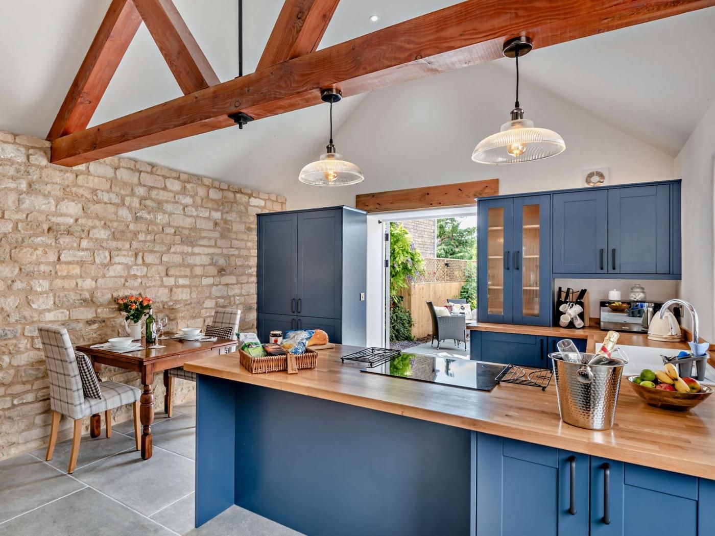 A modern kitchen with a large island, dark blue cabinets, and exposed wooden beams.