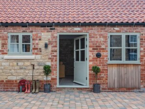 A brick building with a tiled roof, a front door, two windows, and a wooden gate. - 1 Bed in Lincoln (oc-92784) (Kirkby Green)