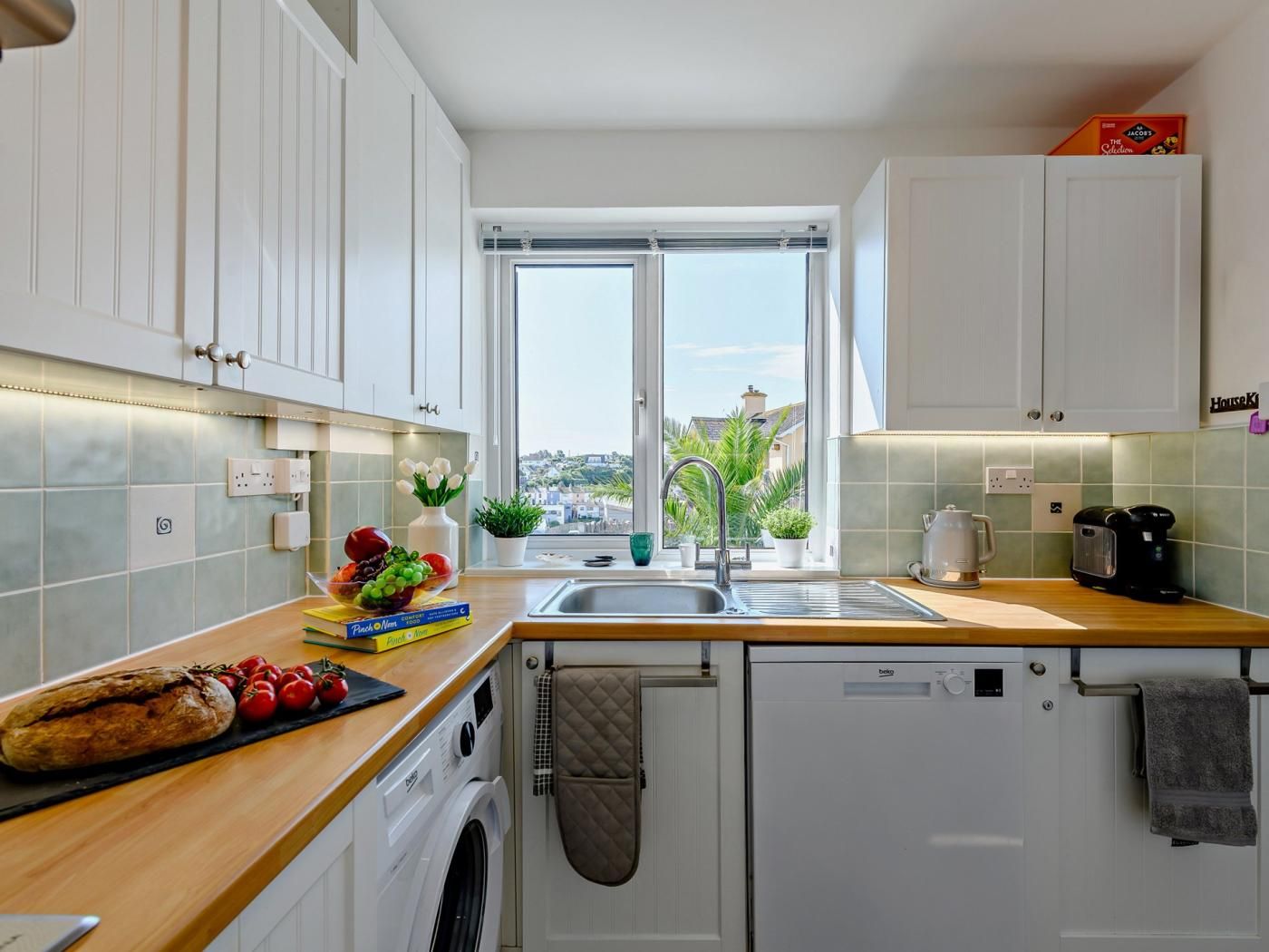 A modern kitchen with a view of the city, a washing machine, and a coffee maker.