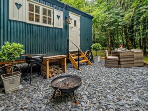 A rustic outdoor setting with a wooden grill, a small table with chairs, and a corrugated metal building. - 1 Bed in Newport (oc-92830) (Newport)