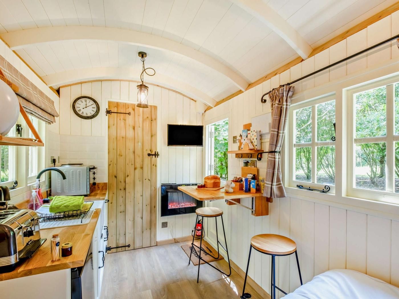 Ein gemütliches Blockhaus-Interieur mit einer Holztür, einem Fernseher, einem Kamin und einem Fenster mit Vorhängen.