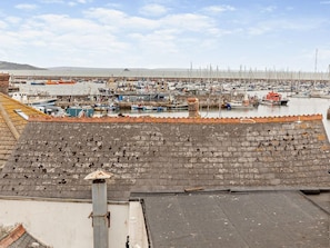 A marina with boats docked, a brick wall in the foreground, and a clear sky. - 3 Bed in Brixham (oc-92821) (Brixham)