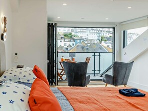 A modern room with a bed, two chairs, a table with breakfast items, and a balcony with a city view. - 3 Bed in Brixham (oc-92821) (Brixham)