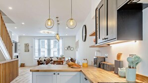 Una cocina moderna con una isla central, luces colgantes y armarios de madera.