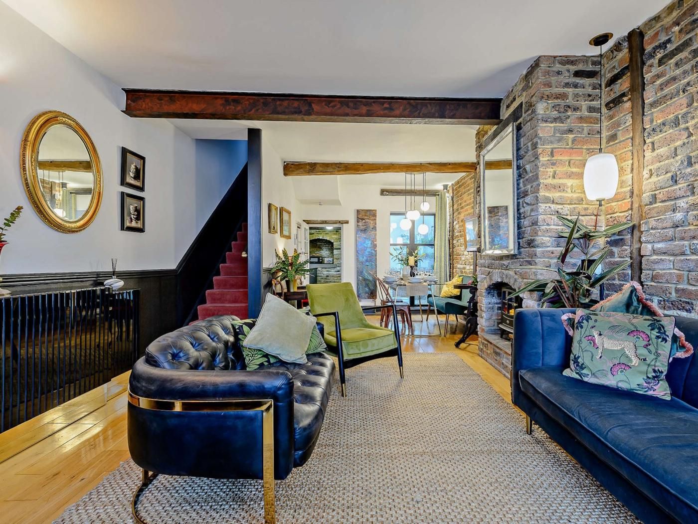 A modern living room with a fireplace, a staircase, and a dining area.