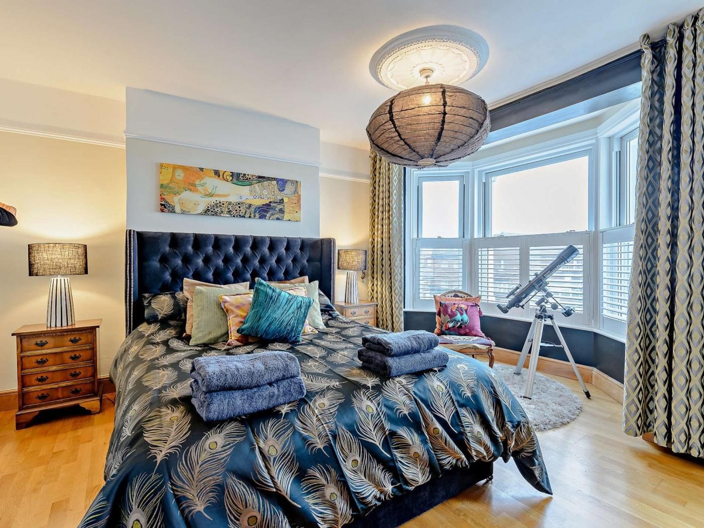 A bedroom with a large bed, a telescope, and a window with curtains.