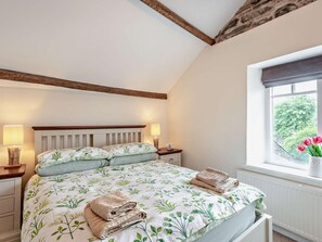 Ein Schlafzimmer mit einem Bett, Nachttischlampen, einem Fenster mit Blick und einem Holzbalken an der Decke.