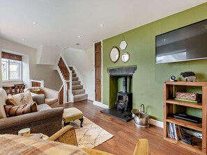 Ein Wohnzimmer mit Treppe, Kamin, Flachbildfernseher und Bücherregal.