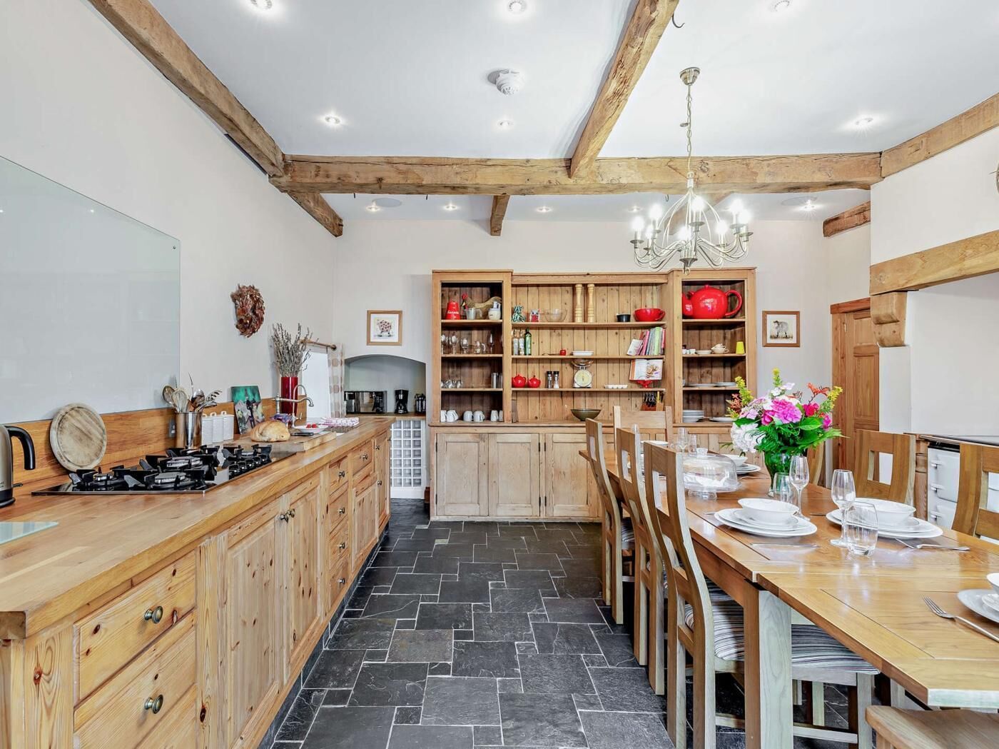 A kitchen with wooden cabinets, a dining table set for four, and a chandelier.