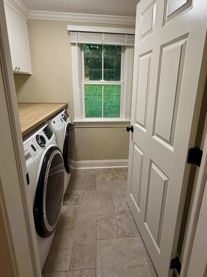 A laundry room with a washing machine, dryer, and a window with a view of a green lawn. - Newly renovated 2bed/2 bath, pet friendly, easy walk to village! (Skaneateles)