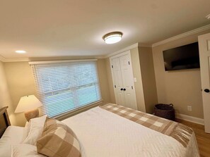 A bedroom with a bed, a window with blinds, a ceiling light, a wardrobe, and a television on the wall. - Newly renovated 2bed/2 bath, pet friendly, easy walk to village! (Skaneateles)