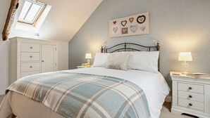A bedroom with a bed, two bedside tables, a dresser, a skylight, and a wall with heart-shaped decorations. - 3 Bed in Wigton (oc-92826) (Torpenhow)