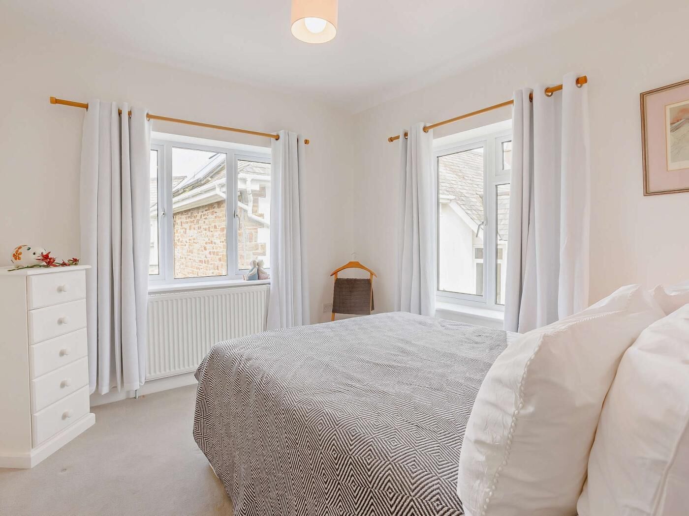Une chambre à coucher avec un lit, une commode, une fenêtre et un radiateur.