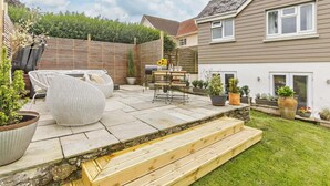 A patio with outdoor furniture, a barbecue grill, and a wooden staircase leading to a house. - 3 Bed in Bideford (oc-92882) (Bideford)