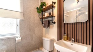 A bathroom with a toilet, sink, mirror, towel rack, and a window. - 2 Bed in Seahouses (oc-92880) (Seahouses)