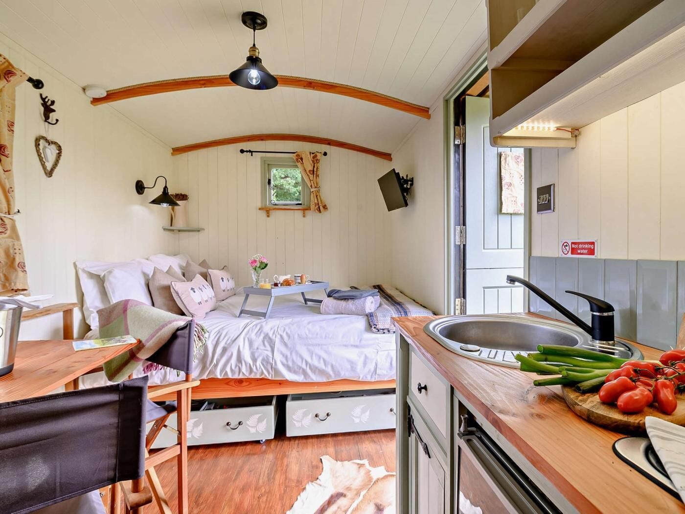 Een gezellige kamer met een bed, bureau en kitchenette.