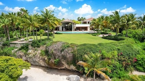 Ein Resort mit Swimmingpool, Palmen und einem Gebäude mit einem Reetdach.