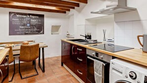 Una cucina moderna con travi in legno, una lavagna con attrazioni locali, un'area pranzo con una sedia e una lavatrice.