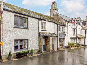 A row of traditional white buildings with stone foundations, a wet street, and a clear sky. - 2 Bed in Looe (oc-92919) (Polperro)