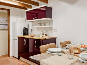 A compact kitchen with a refrigerator, coffee maker, and a shelf with jars. - 2 Bed in Looe (oc-92919) (Polperro)