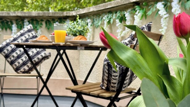 Uma área externa com mesa, cadeiras e um vaso de planta.