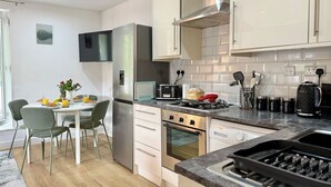 Uma cozinha moderna com área de jantar, eletrodomésticos de aço inoxidável e painel de azulejos.