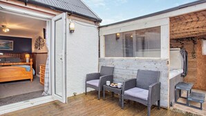 Une pièce confortable avec un lit, une petite table sur laquelle sont disposées des tasses et des pâtisseries, et un fauteuil en osier.