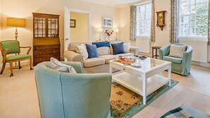 A living room with a sofa, armchairs, a coffee table, a cabinet, and a clock on the wall. - 2 Bed in Blairgowrie (oc-92998) (Alyth)