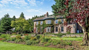 A large, two-story stone building with a well-maintained lawn and garden in front. - 2 Bed in Blairgowrie (oc-92998) (Alyth)