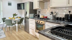 Una cocina moderna con comedor, electrodomésticos de acero inoxidable y un televisor de pantalla plana.