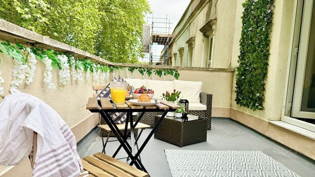 Un patio con mesa, sillas, sofá y un pequeño jardín con plantas.