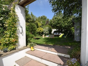 A garden with a lawn, a play area including a slide, and a brick pathway leading to a door. - 4 Bed in Bideford (oc-93051) (Appledore)