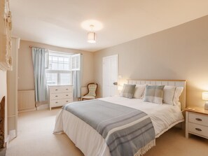 A bedroom with a bed, bedside tables, a chair, a radiator, and a window with curtains. - 4 Bed in Bideford (oc-93051) (Appledore)
